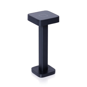 The ZODAX MONZA RECHARGEABLE TABLE LIGHT is a black, rectangular, pedestal-shaped device with a square touchpad on top, offering USB rechargeable capability and adjustable light intensity, shown upright on a white background.