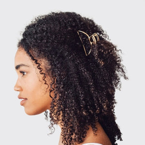The KITSCH - OPEN SHAPE CLAW CLIP IN GOLD is a minimalist gold metal hair accessory from KITSCH, ideal for styling thick hair and showcased against a plain light background.