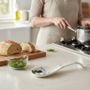 The FEARRINGTON SIGNATURE COLLECTION - BELTIE SPOON REST BY VIETRI features a playful black and white Beltie cow design with a UFO beam—an eye-catching, quirky accent from VIETRI that brings Fearrington Village charm to your kitchen.