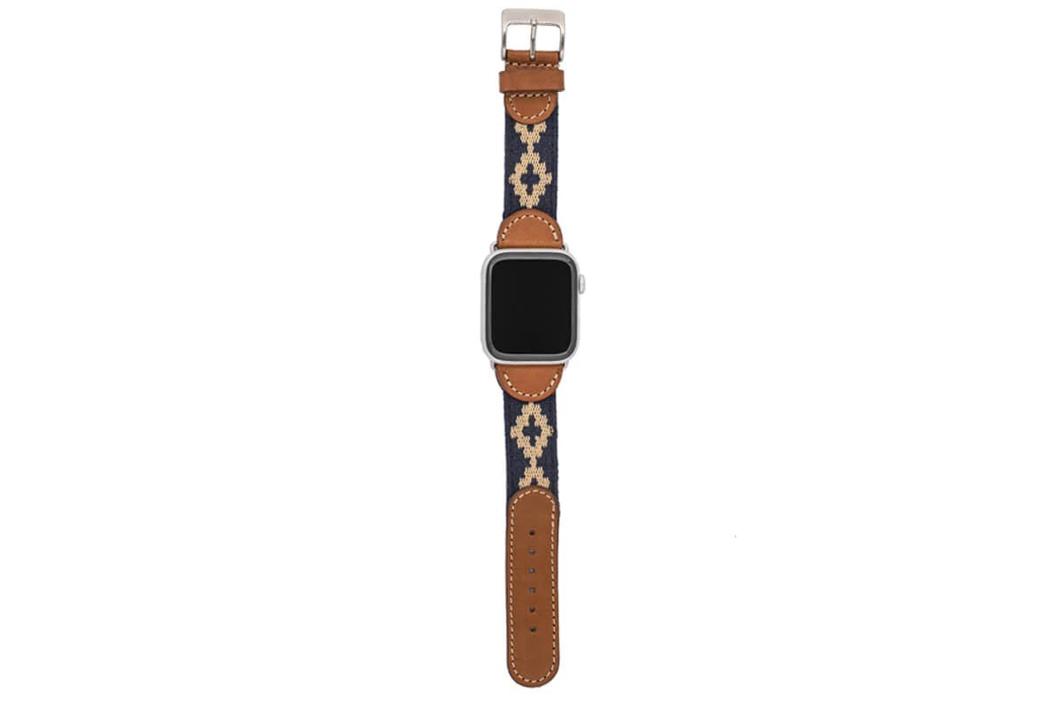 The LA MATERA - CORBINA Apple Watch Band in silver pairs artisan brown leather with a black fabric section, beige geometric pattern, and red stitching.