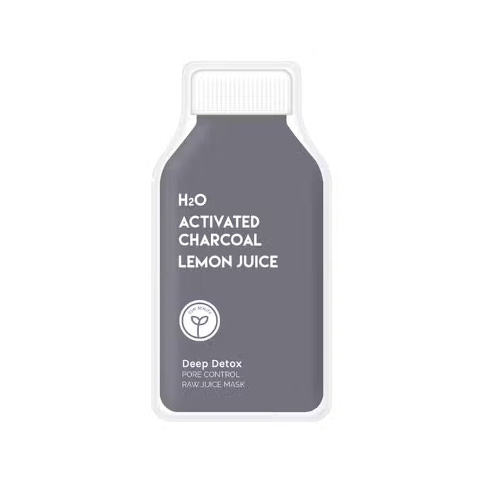 A bottle of ESW BEAUTY - H2O Charcoal Lemon Juice Mask sits on a white surface with lemon halves, a whole lemon, a bowl of white powder, a wooden spoon, and ESW Beauty’s black charcoal powder.