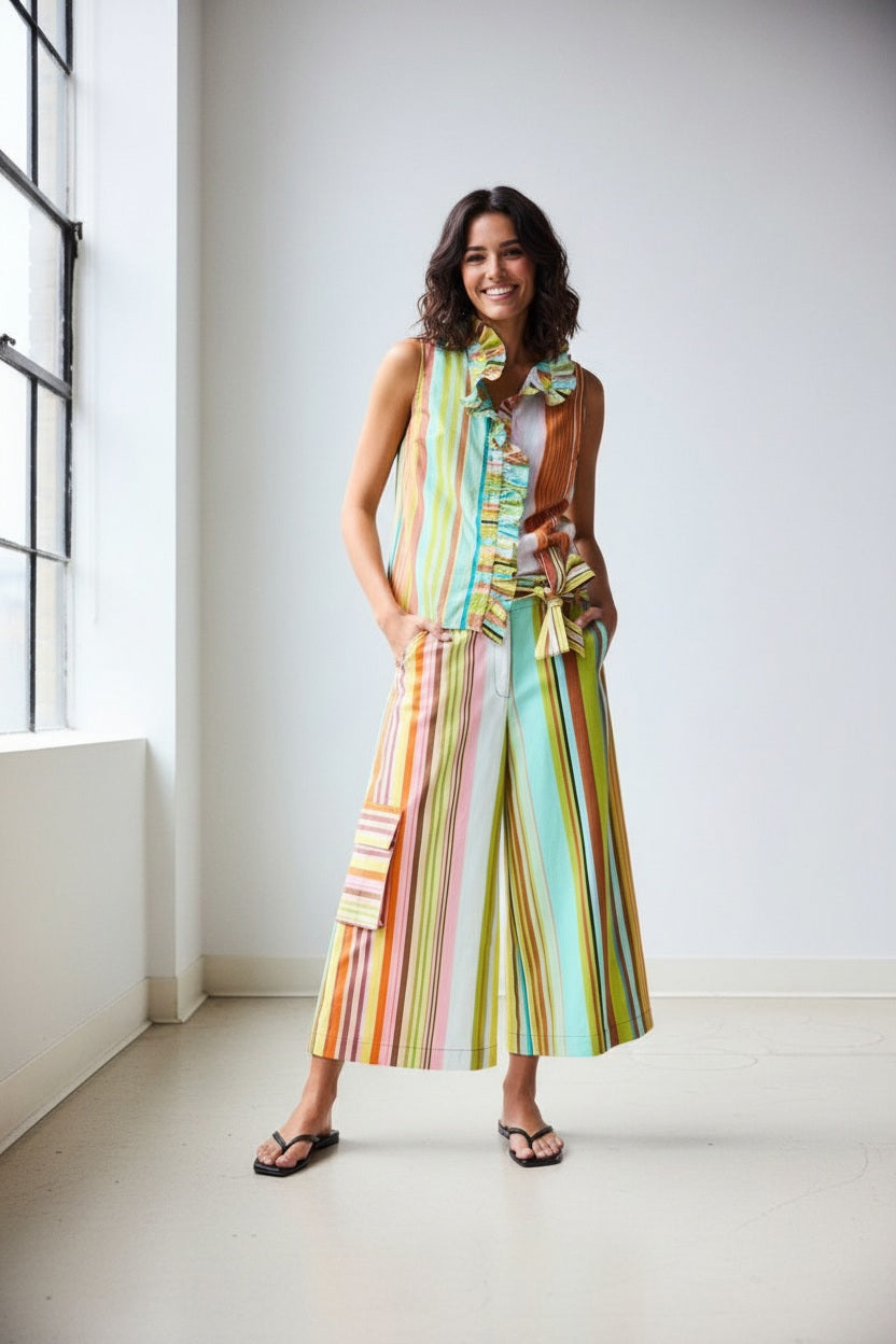 A person, seen from the back with hands on hips, wears the HOPE FOR FLOWERS - CROPPED PANT IN COMBO STRIPES: a colorful, striped matching set featuring wide leg cropped pants by HOPE FOR FLOWERS.