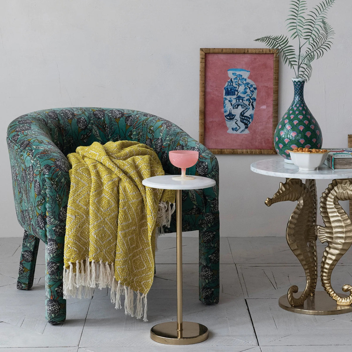 The CREATIVE COOP MARBLE TOP GOLD MARTINI TABLE features a white marble top, a slim gold pedestal stem, and a circular gold base, shown against a white background.
