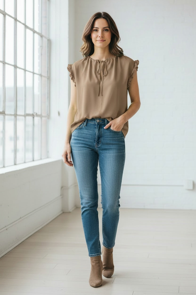 A woman wears the MEIMEIJ Cap Sleeve Blouse, a light green viscose top with ruffle cap sleeves and a tied neckline from MEIMEIJ, paired with white bottoms against a plain light background.