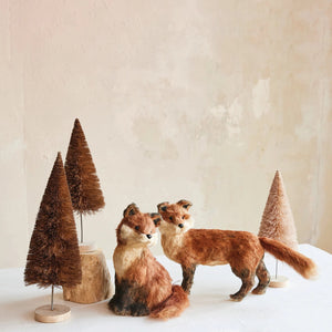 The CREATIVE COOP SISAL SITTING FOX features reddish-brown fur, black-tipped ears, a bushy tail, and tan accents—an adorable plush decor piece for any space.