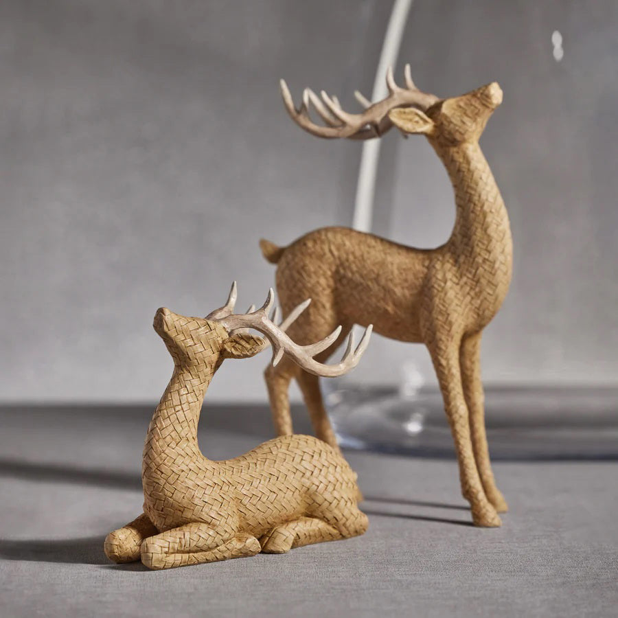 The ZODAX RATTAN SITTING DEER is a decorative sculpture with large antlers and a woven, basket-like texture in light brown, measuring 22.23 x 19.05 cm (8.75 x 7.5 in), displayed against a plain white background.