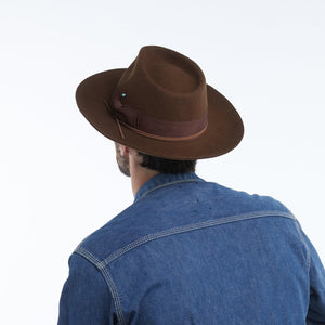 The WYETH - TEDDY HAT IN BROWN by WYETH is a vintage-inspired wide-brimmed fedora with a matching dark brown ribbon band, shown against a plain white background.