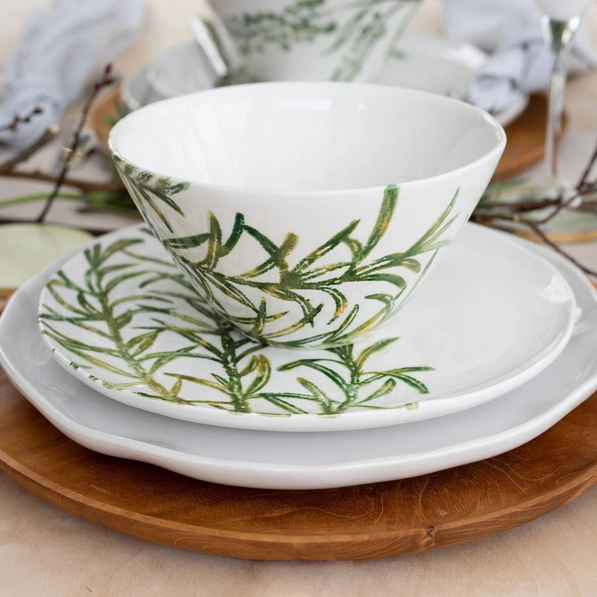 The VIETRI - Fauna Cereal Bowl is a small, white ceramic piece adorned with delicately painted green leaf designs on the exterior, evoking the lush greenery of Umbria. This bowl features a simple, elegant shape with a slightly flared rim and a smooth finish.