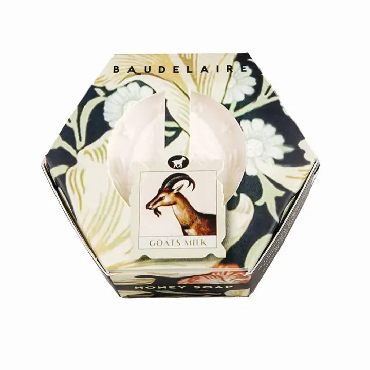 A partially open hexagonal box of BAUDELAIRE GOATS MILK HONEY SOAP 3.5OZ reveals the soap inside. The floral packaging with a goat’s head image makes it ideal for sensitive skin.