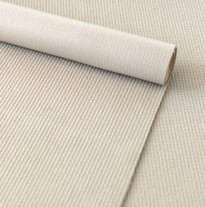 A close-up of the ANNIE SELKE - EXTRA GRIP RUG PAD 2X8 partially rolled out on a matching surface, highlighting its ribbed texture and soft material.