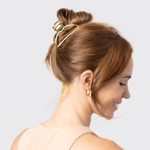 The KITSCH - OPEN SHAPE CLAW CLIP IN GOLD is a minimalist gold metal hair accessory from KITSCH, ideal for styling thick hair and showcased against a plain light background.