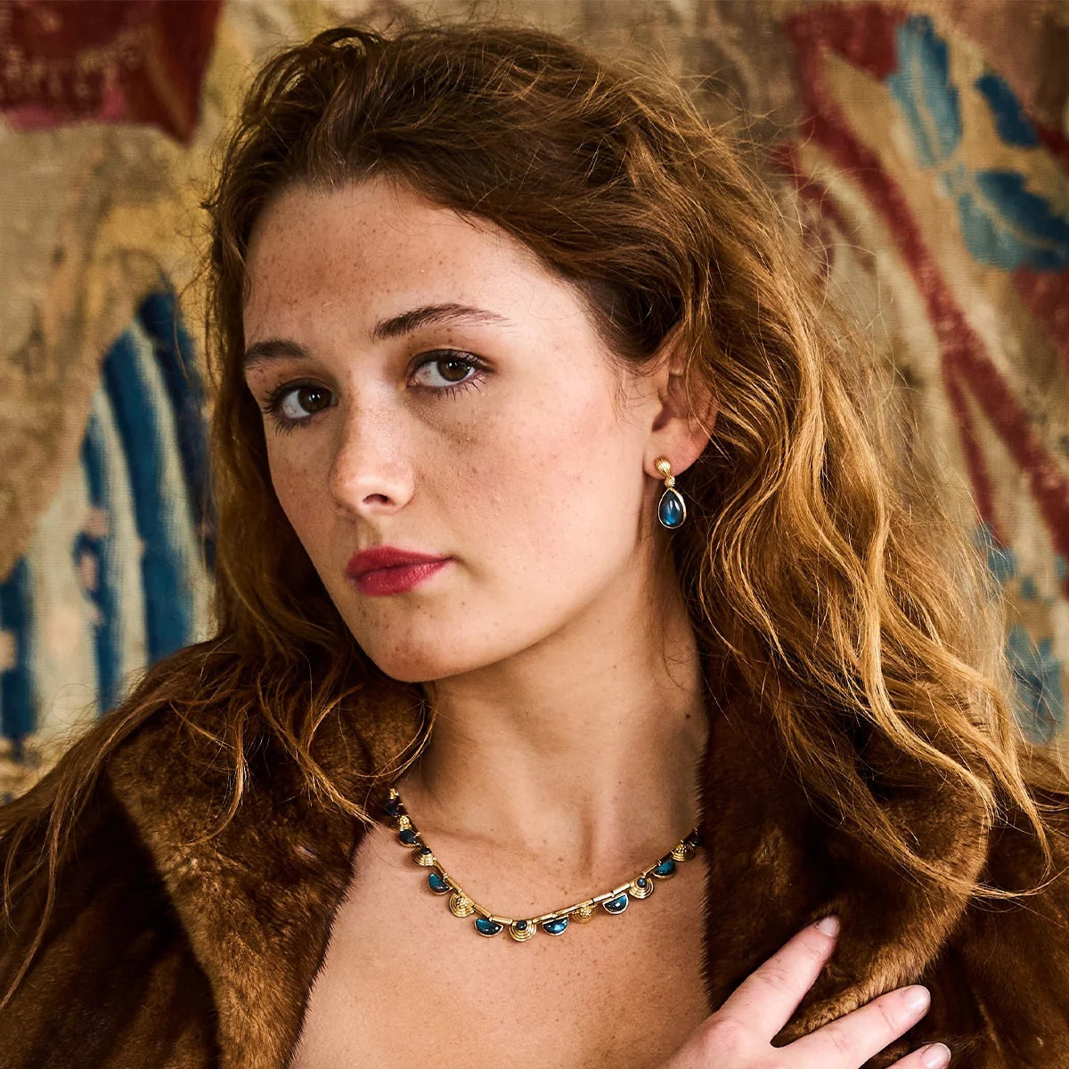 The CAPUCINE DE WULF - MONIQUE GEM POST EARRINGS feature teardrop-shaped blue labradorite gemstones accented by small gold bead clusters and textured gold detailing at the tops. These 18K gold plated earrings by CAPUCINE DE WULF are a stunning example of handmade jewelry, perfect for elevating any look.