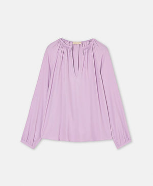 The MOMONI LARICE SHIRT is a long-sleeved, light purple bohemian blouse featuring a gathered neckline, subtle V-front slit, and loose fit, shown on a white background.