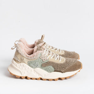 The FLOWER MOUNTAIN - KOTETSU SNEAKER by FLOWER MOUNTAIN/FALC USA is a stylish pair of beige and olive green shearling sneakers, featuring a textured, fluffy lining and trekking-style lacing in white. They come with a thick, white and brown patterned sole and an embroidered flower design on the side. Additionally, they have a pull tab on the heel. The sneakers are displayed against a plain white background.