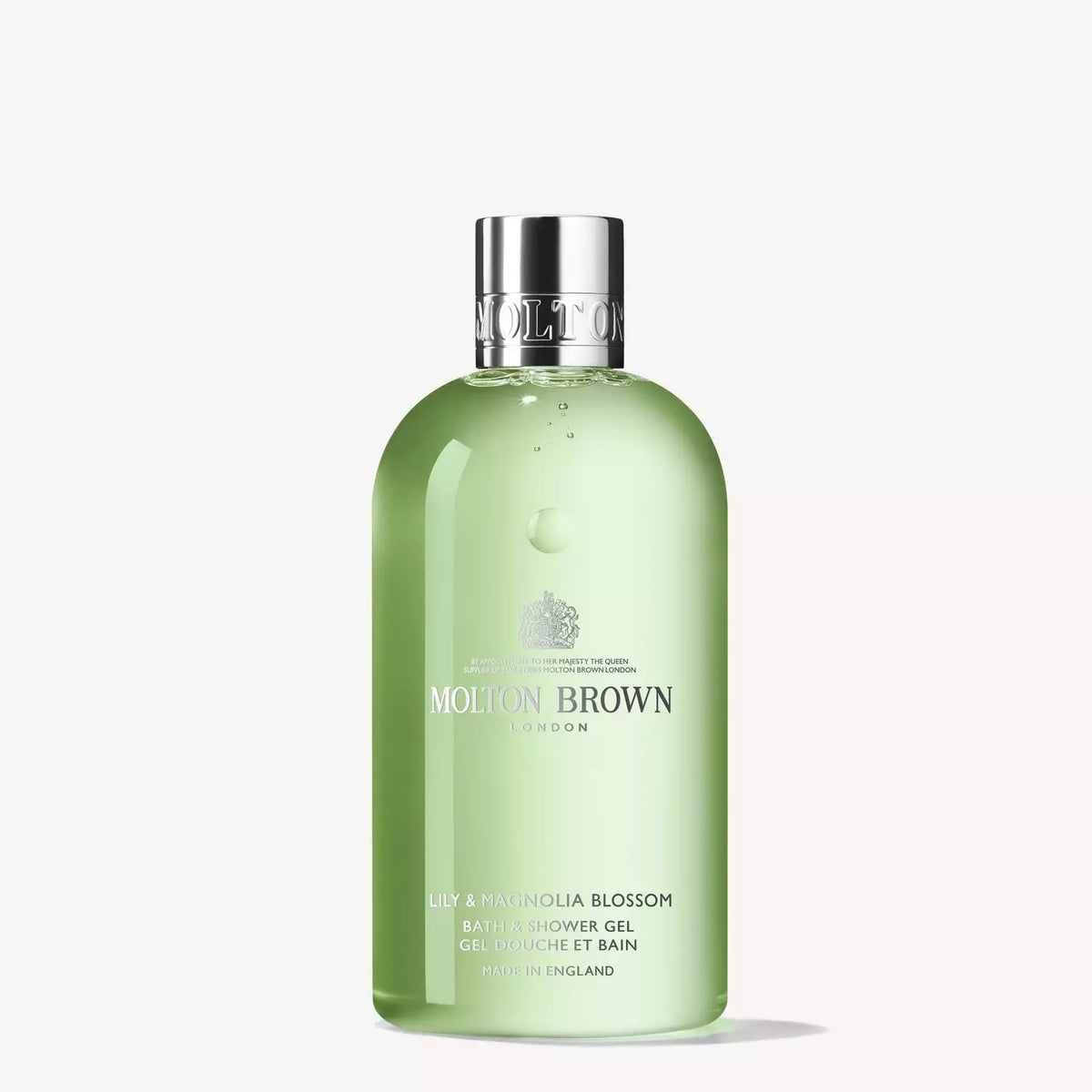 A clear bottle of MOLTON BROWN - LILY AND MAGNOLIA BATH AND SHOWER GEL with a silver cap. This white-floral wash features a light green gel, infused with magnolia, and has brand and product details in crisp white text on the front.
