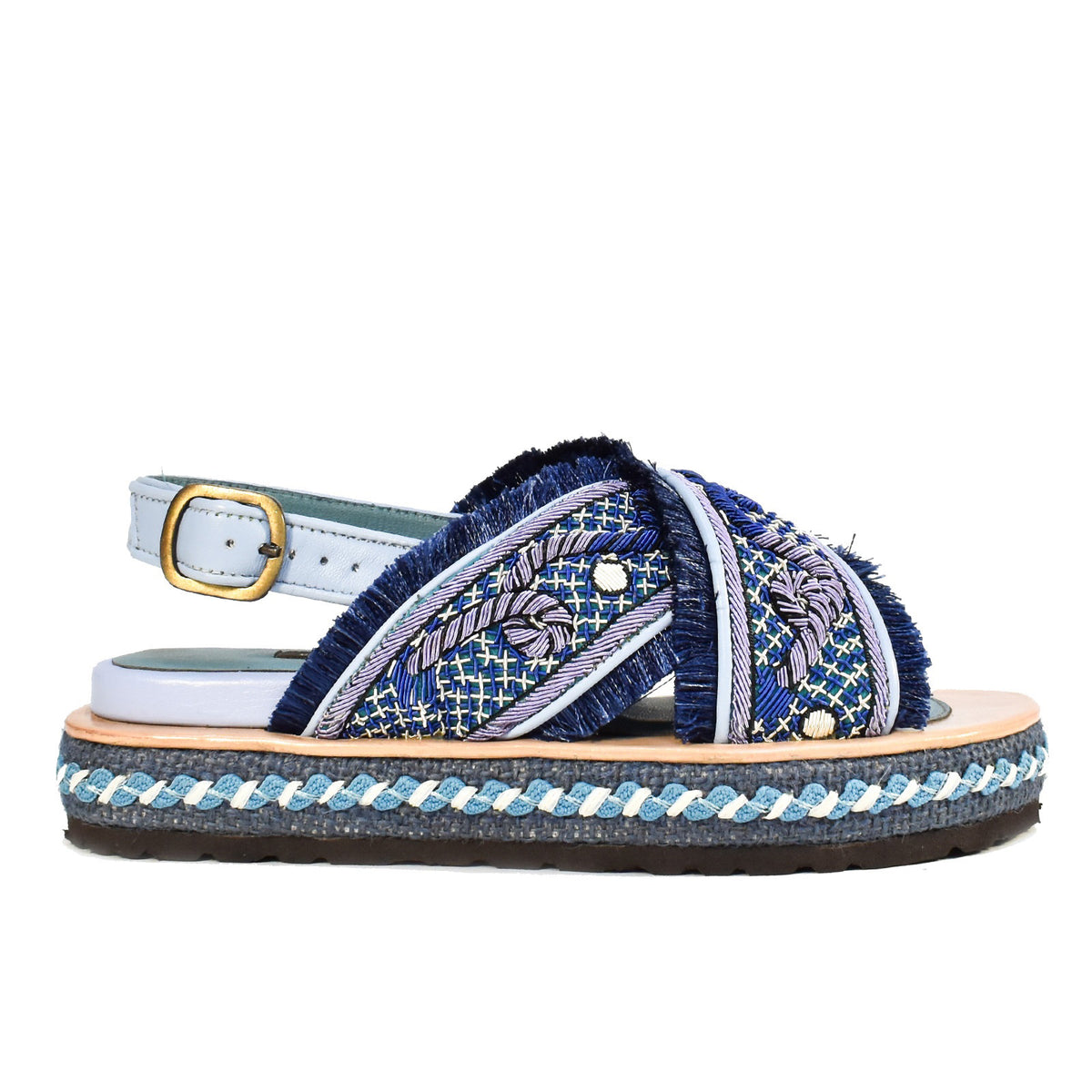 Introducing the MEHER KAKALIA DA GAMMA BLOC SANDAL in Yacht Blue Deep Blue: a chic sandal with blue cross-straps, intricate hand embroidery, frayed edges, and a decorative platform sole featuring blue and white braid accents. It includes an adjustable ankle strap with a gold buckle.