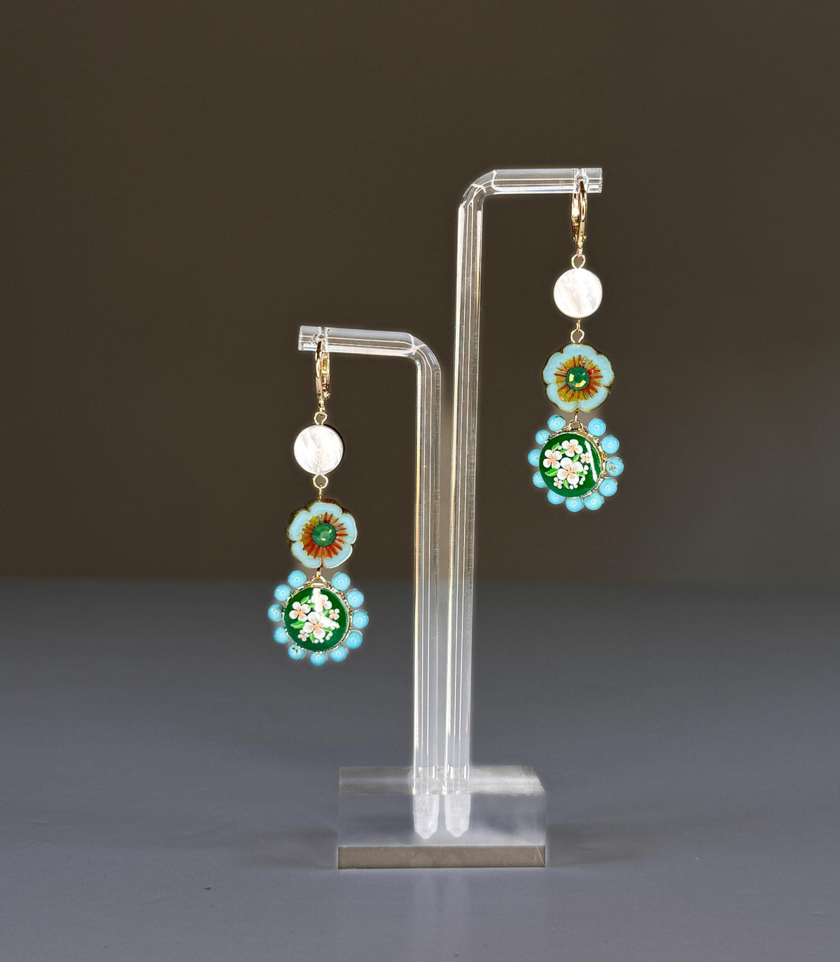 The SANDRINE FRANCE STUDIO - MOLLY EARRINGS by SANDRINE FRANCE STUDIO are handmade in NYC, featuring gold hoops with white discs, blue-green floral beads, brown centers, green pendants, vintage Japanese glass, and turquoise accents.
