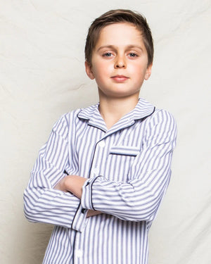 The PETITE PLUME FEARRINGTON LIFESTYLE COLLECTION - CHILDREN'S TWILL NAVY FRENCH TICKING PAJAMA SET is a delightful option for kids, featuring long sleeves and pants with chic vertical white and gray stripes. This set is crafted from yarn-dyed cotton, boasting a top with a collar, full button-down front, and a single chest pocket adorned with matching fabric piping along the cuffs and pocket opening.