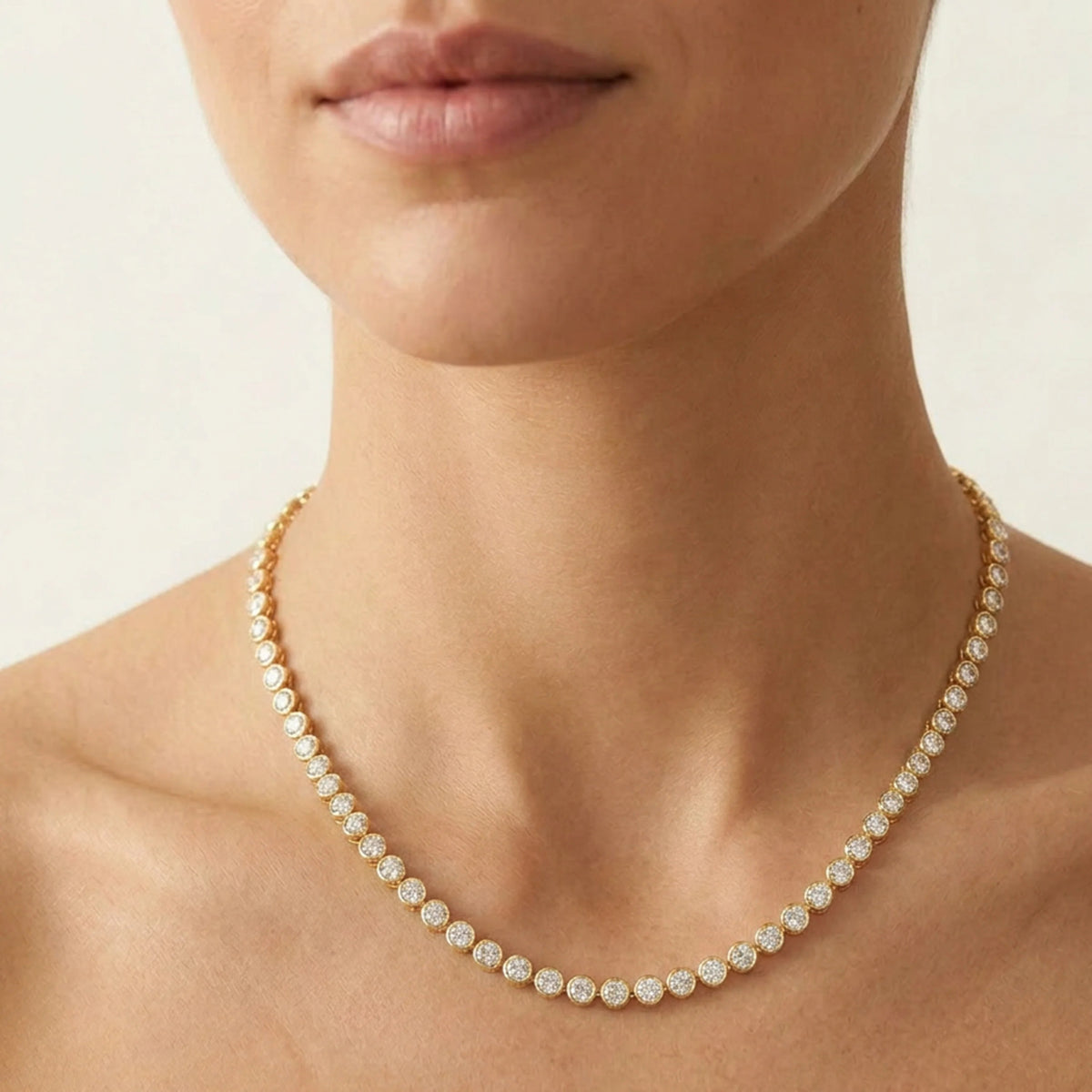 The ELLA STEIN - DIAMOND ESSENTIAL TENNIS NECKLACE by ELLA STEIN is a gold-plated piece adorned with a continuous row of evenly spaced round, white gemstones along the chain, beautifully displayed on a white background. This elegant necklace blends classic design with the lasting durability of stainless steel.