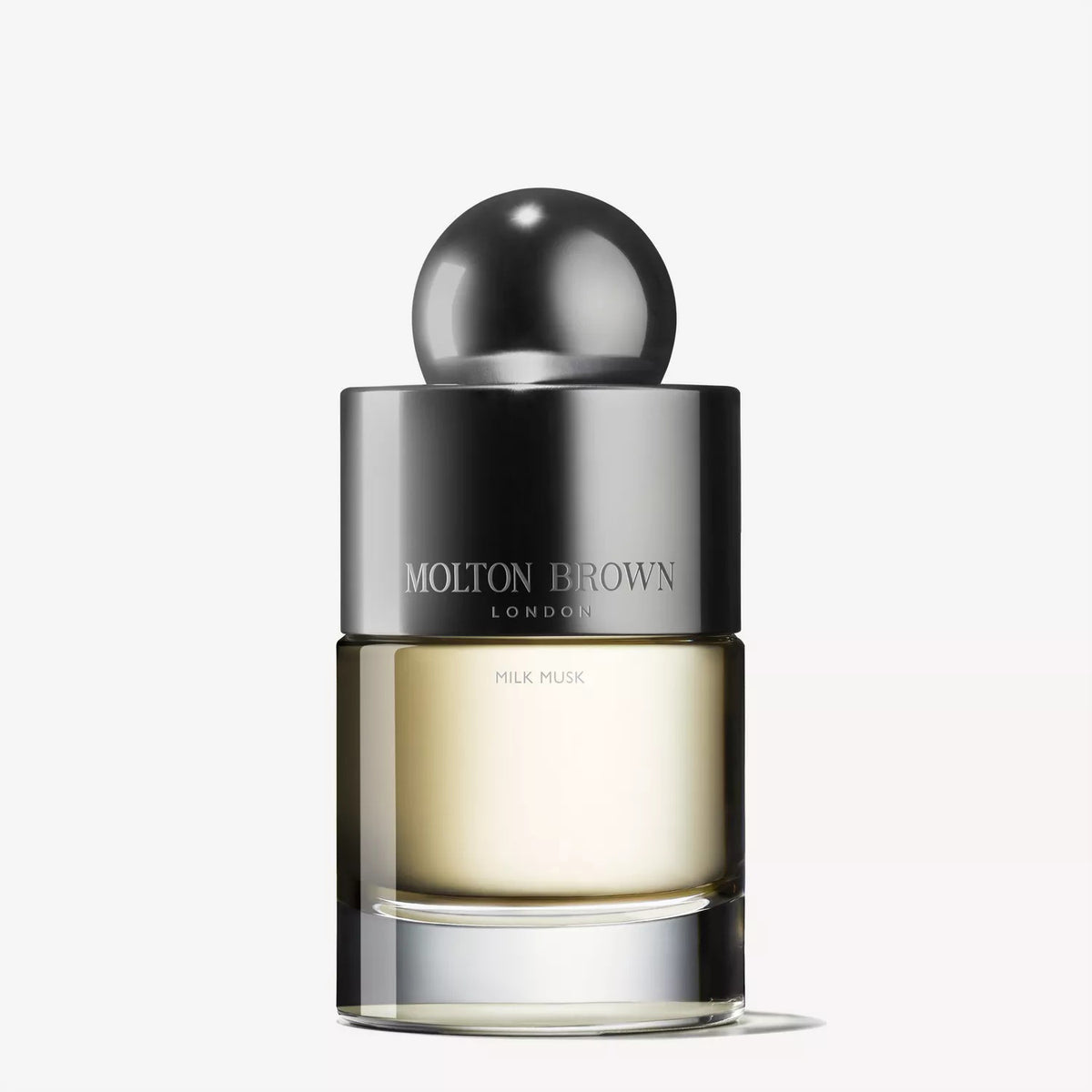 A 3.4fl oz bottle of MOLTON BROWN Milk Musk Eau de Toilette, featuring a silver spherical cap and gradient clear-to-amber glass, sits against a white background, showcasing this soft floral-musky fragrance.