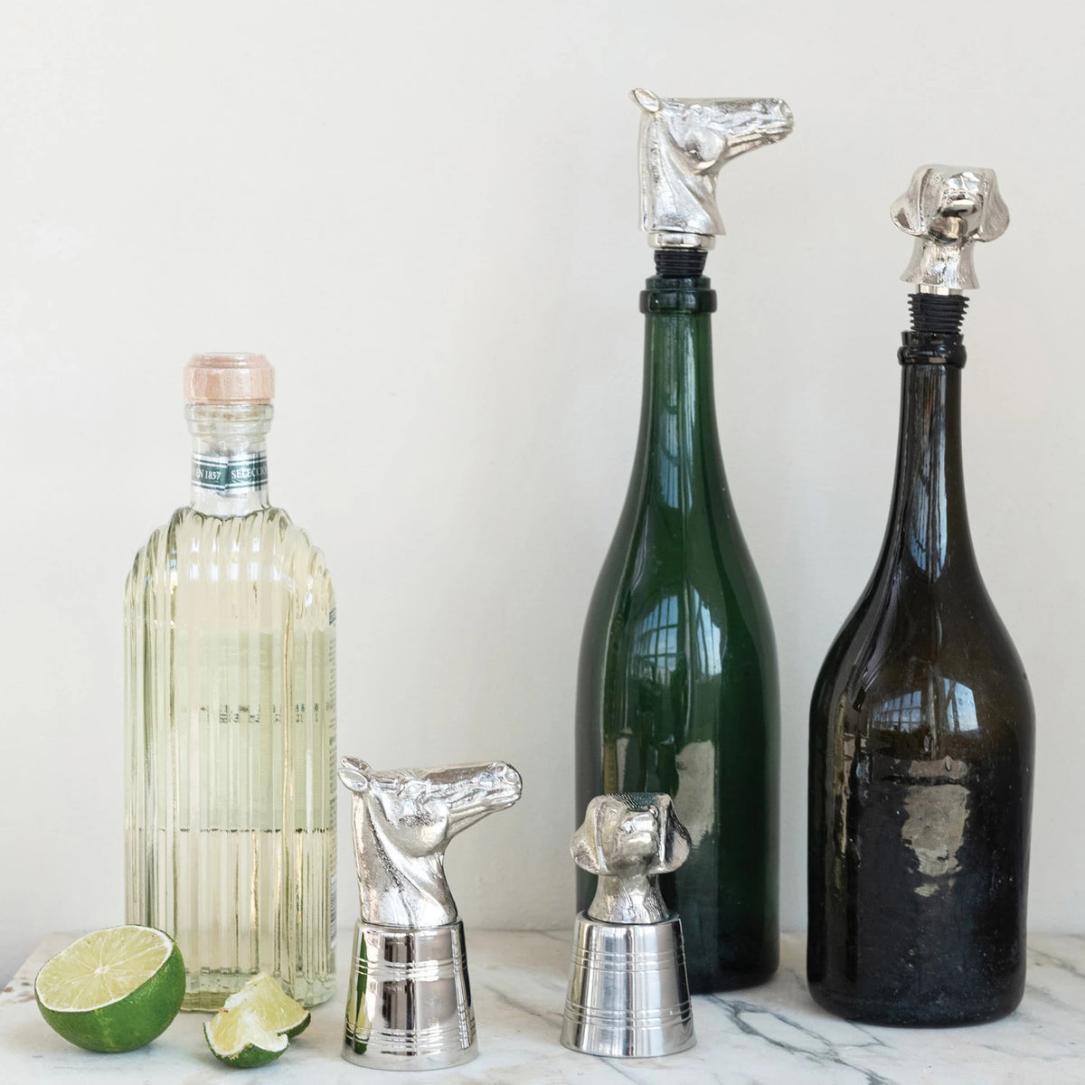 The CAST ALUMINUM DOG HEAD JIGGER by CREATIVE COOP is a silver bottle stopper shaped like a dog&#39;s head, featuring detailed fur textures and a cylindrical base with horizontal grooves for a secure fit.