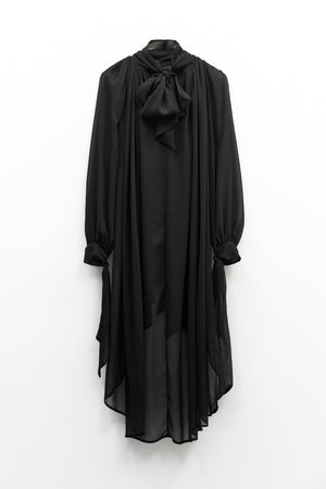 The ELEH - THE CHIFFON TIE NECK TOP by ELEH is a sheer black chiffon blouse with long sleeves, a high neckline, and an oversized bow tie at the collar—an elegant evening statement inspired by classic blouses.