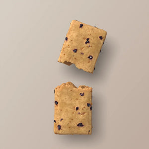 A blue wrapper labeled “STARS+HONEY - MAPLE BLUEBERRY MUFFIN”—a tasty collagen protein bar blending maple and blueberry flavors from the brand STARS+HONEY—rests on a beige surface, with nutritional information visible.