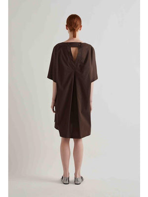 A person with straight red hair stands against a plain light background, wearing the MEIMEIJ oversized cotton shift dress in black by MEIMEIJ and silver flat shoes.