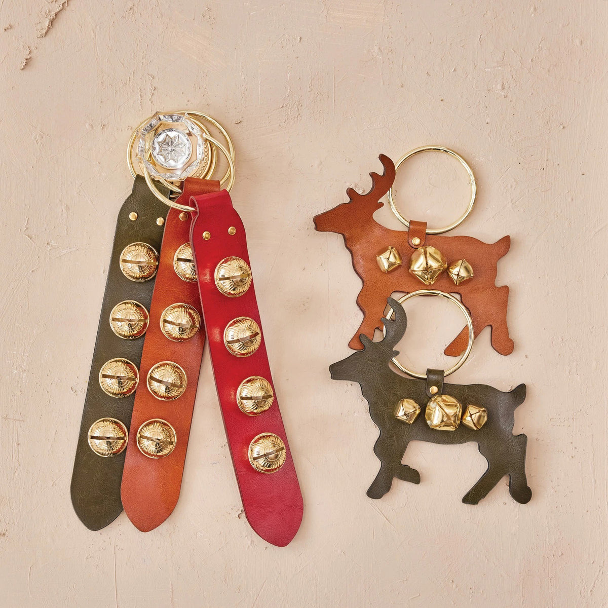 The LEATHER AND BELL DOOR HANGER by CREATIVE COOP comes in red, black, and brown leather with gold keyrings and studs—offering a classic door hanger look for a stylish way to accent your keys or bag.