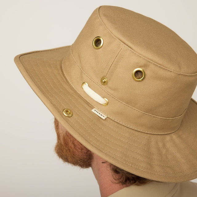 A man with a reddish beard and mustache wears the TILLEY - CLASSIC T3 HAT IN DARK KHAKI and a matching collared shirt, looking at the camera. This TILLEY hat offers UPF 50+ protection and is made in Canada.