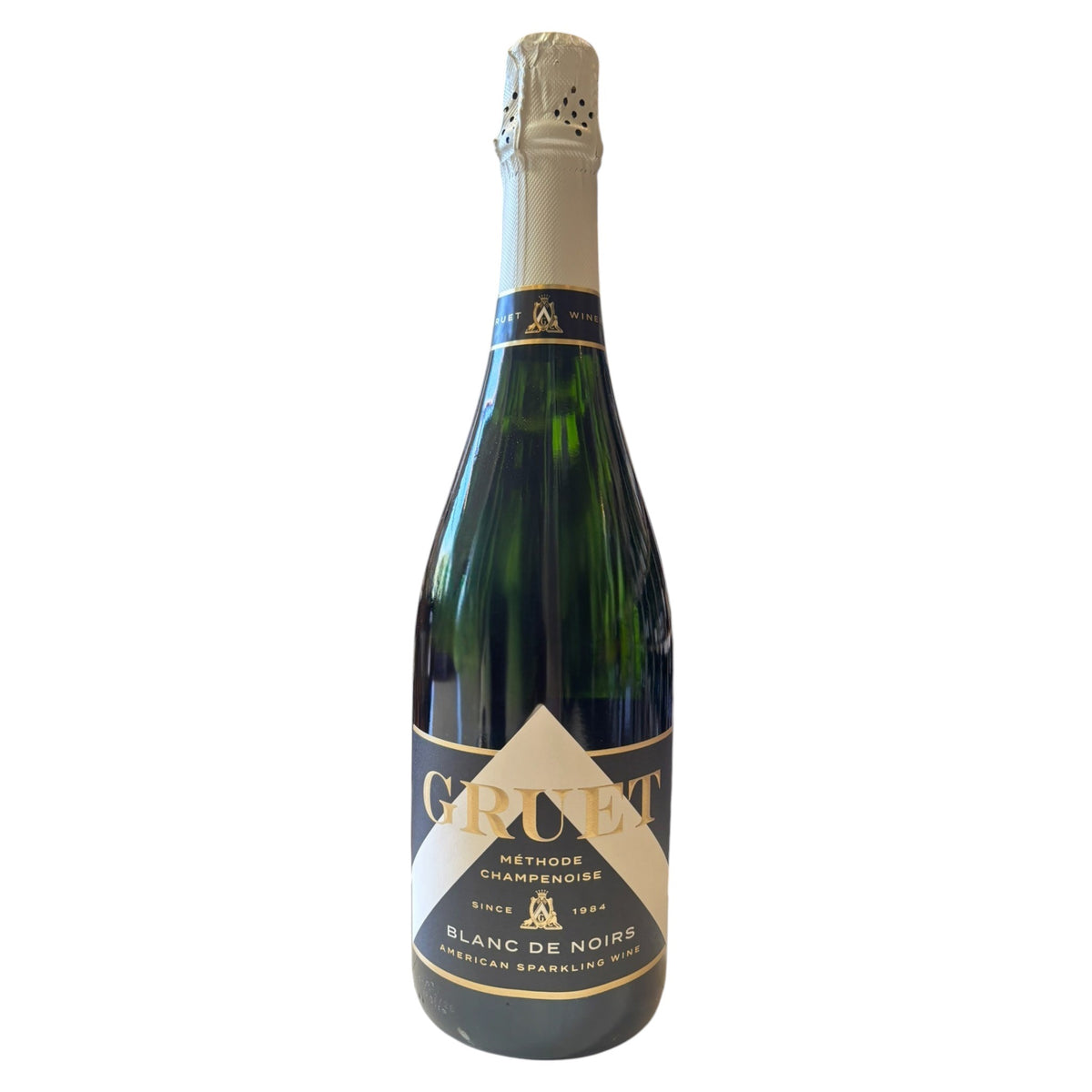 A bottle of Gruet Blanc de Noirs sparkling wine from New Mexico, crafted using the Champagne method, has a green glass body, beige foil on the neck, and a white label with black text for Wine: Empire Distributing.