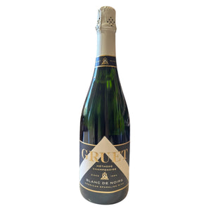 A bottle of Gruet Blanc de Noirs sparkling wine from New Mexico, crafted using the Champagne method, has a green glass body, beige foil on the neck, and a white label with black text for Wine: Empire Distributing.