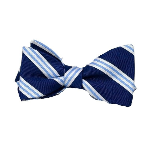 The BIRD DOG BAY - On Air Stripe Silk Bow Tie in Navy and Blue by BIRD DOG BAY showcases diagonal white and light blue stripes on a navy background. This handmade silk bow tie, crafted in the USA, is displayed against a plain white backdrop.
