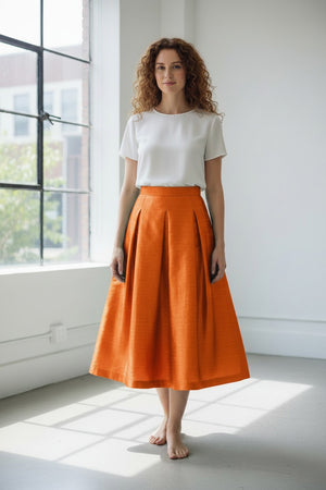 The MIDI STRUCTURED SKIRT by ALYKI LABORATORIO is a high-waisted, midi-length piece with a flared silhouette, showcasing a vibrant pink and red abstract floral print on a white background.