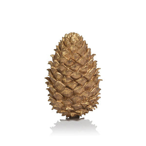 Three ZODAX LARGE GOLDEN PINECONE ornaments hang from satin ribbons against a warm brown background, adding a touch of handcrafted holiday décor to the scene.