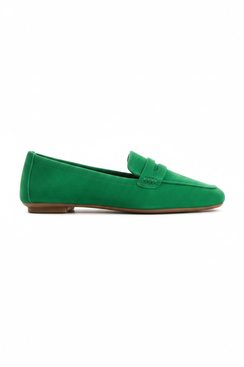 A person stands on a light floor wearing blue jeans and REQINS - HEMA SUEDE LOAFER IN GAZON GREEN by REQINS, featuring a leather insole.