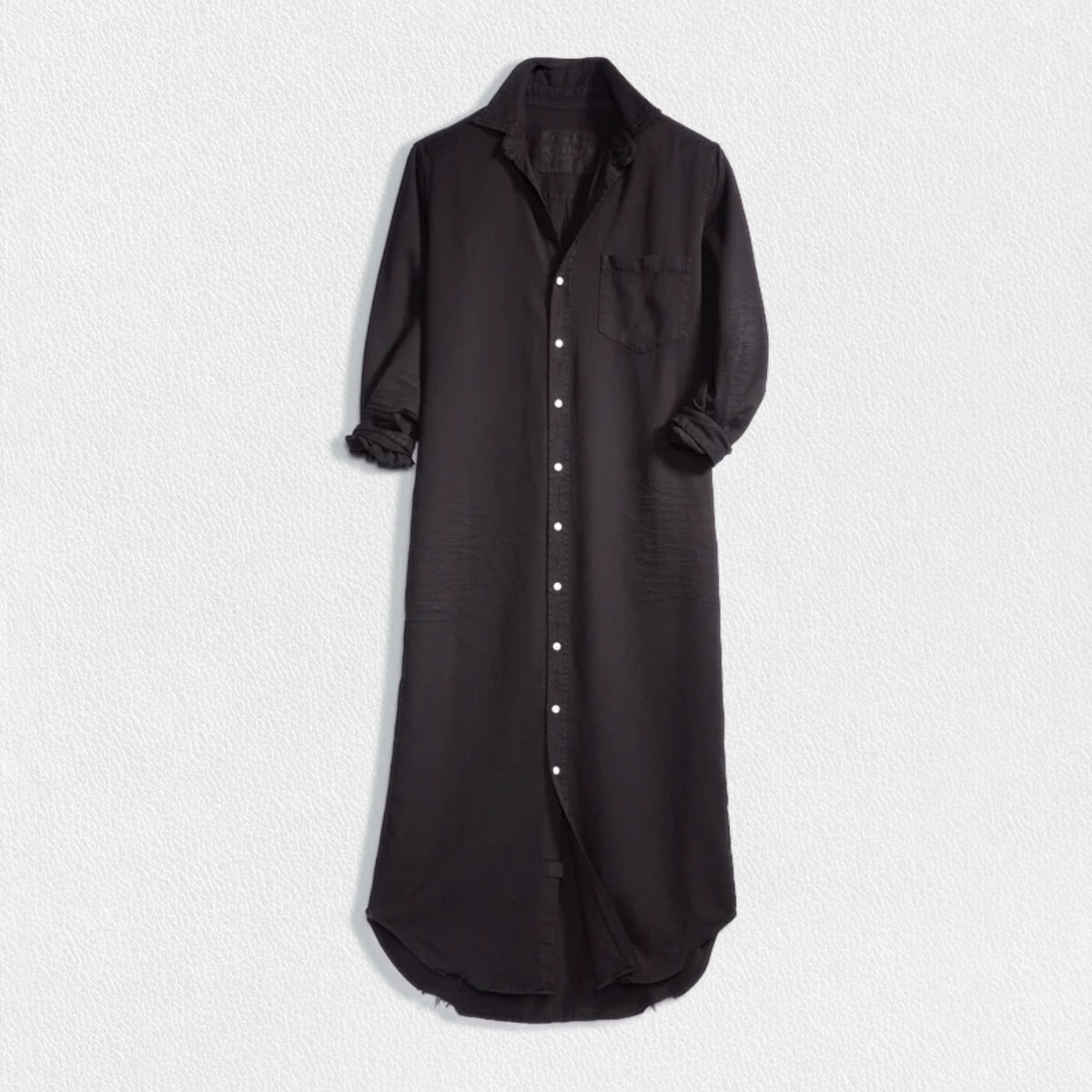 The dress is a FRANK &amp; EILEEN RORY Maxi Shirtdress in Famous Denim Black. It has a collar, rolled-up sleeves, a single chest pocket on the left side, and a curved hem. Crafted from fine Italian cotton, it is displayed against a plain white textured background.
