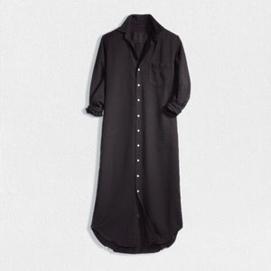 The dress is a FRANK & EILEEN RORY Maxi Shirtdress in Famous Denim Black. It has a collar, rolled-up sleeves, a single chest pocket on the left side, and a curved hem. Crafted from fine Italian cotton, it is displayed against a plain white textured background.