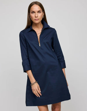 A woman with straight brown hair models the HINSON WU - ALESSA 3/4 SLEEVE DRESS IN STRETCH POLISHED COTTON NAVY, featuring a boxy fit, knee-length cut, three-quarter sleeves, and a visible back gold zipper against a plain background.