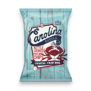A 5oz bag of CAROLINA KETTLE - CRAB BOIL CHIPS by 1 IN 6 SNACKS features a red crab with a scroll on a blue wooden background, accented by bold red and white text.