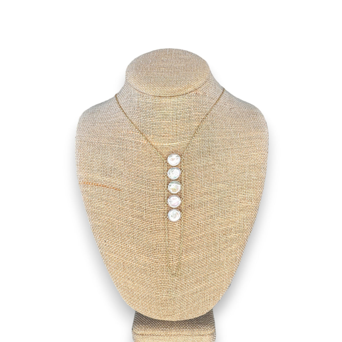 A woman in a beige top wears the GOLDISH - LADDERS TO BLISS PEARL NECKLACE, featuring round white stones, as she poses with crossed arms and a turned head, embodying balance and harmony.
