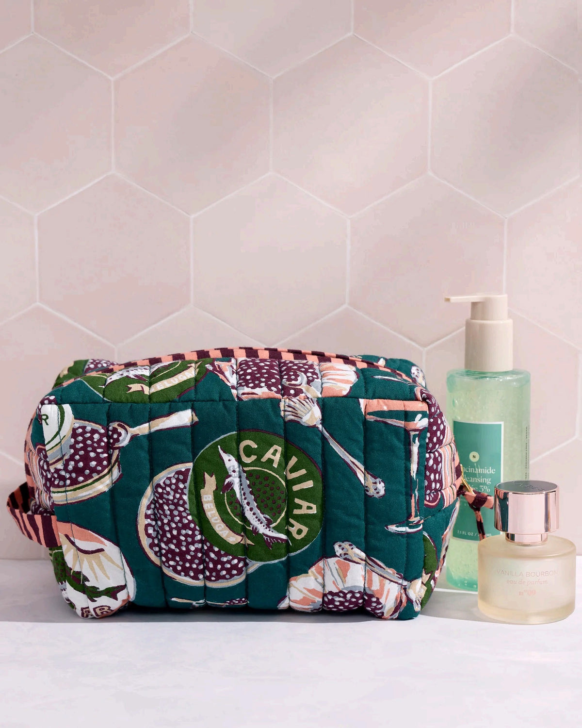 Adorned with an illustrated pattern of caviar tins, open shells brimming with caviar, delicate spoons, and tall champagne glasses on a rich peacock feather green background, the PRINTFRESH - CHAMPAGNE & CAVIAR QUILTED POUCH IN PEACOCK FEATHER is an elegant accessory from PRINTFRESH. This stylish pouch makes a perfect gift for her.