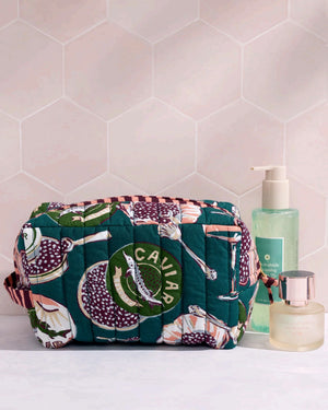 Adorned with an illustrated pattern of caviar tins, open shells brimming with caviar, delicate spoons, and tall champagne glasses on a rich peacock feather green background, the PRINTFRESH - CHAMPAGNE & CAVIAR QUILTED POUCH IN PEACOCK FEATHER is an elegant accessory from PRINTFRESH. This stylish pouch makes a perfect gift for her.