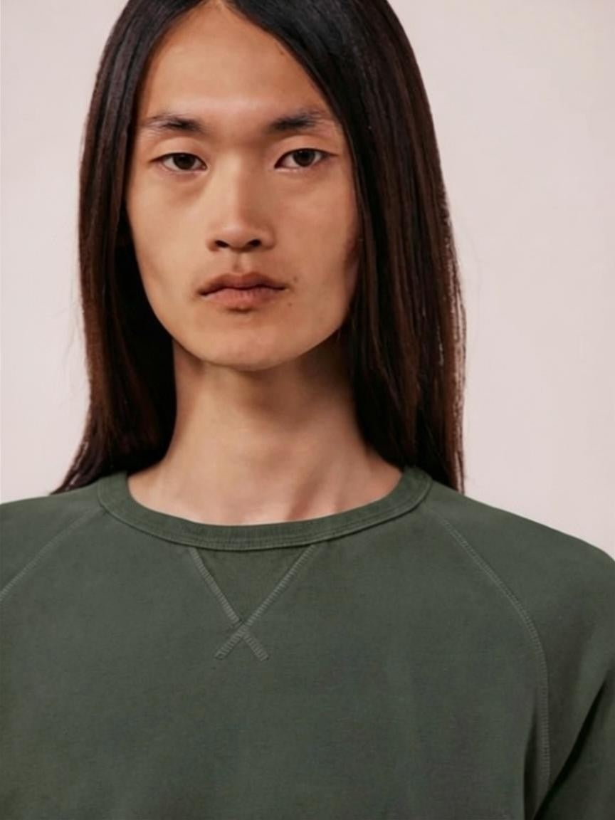 A person with long straight brown hair wears the HARTFORD - LIGHT FLEECE SWEATSHIRT IN ZINC, looking directly at the camera with a neutral expression against a plain light background.