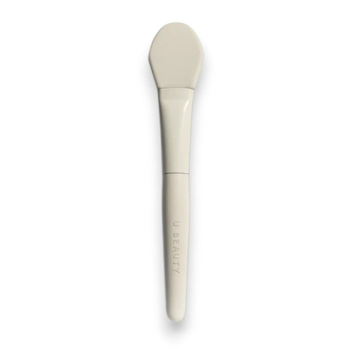 THE BRUSH by U BEAUTY is a white silicone skincare applicator featuring a flat, rounded tip and &quot;U BEAUTY&quot; on the handle—crafted for precision application against a clean, white background.