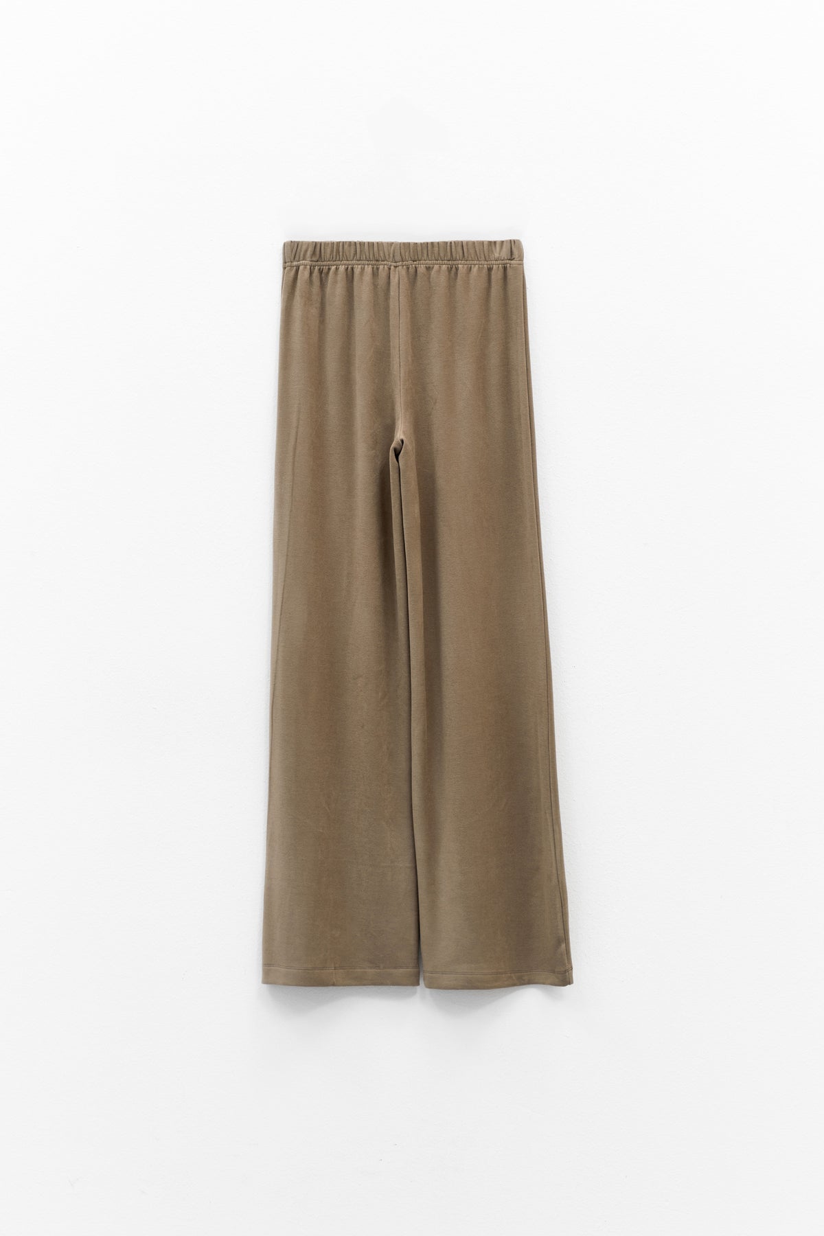 The ELEH - THE SCALA PULL ON SWEATPANT TROUSER by ELEH is a pair of loose-fitting, light brown, velvety pull-on trousers with an elastic waistband, shown against a plain white background.