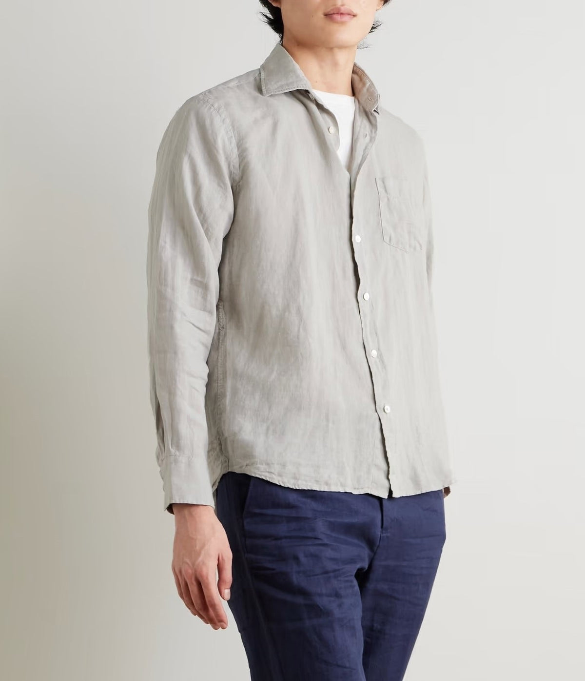 A person wears the HARTFORD - PAUL Linen Shirt in Army over a white tee and navy blue pants, standing against a plain light background.