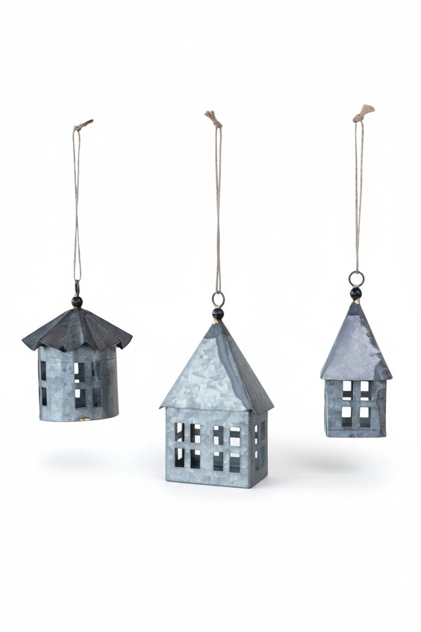 Three Creative Coop Galvanized Metal House ornaments hang by jute string loops as rustic holiday decorative accents.