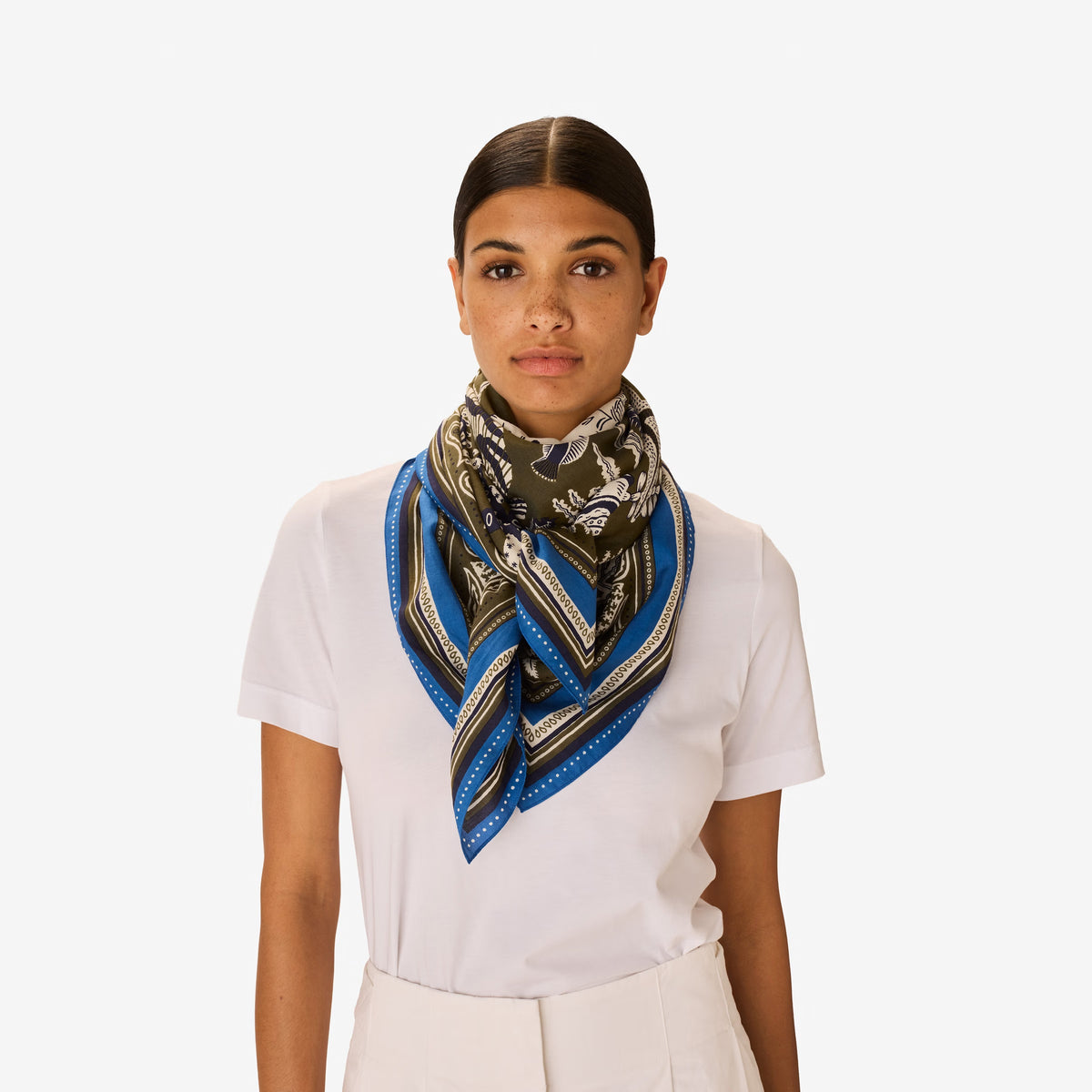 The INOUI EDITIONS - NEPTUNE SCARF IN KHAKI by INOUI features an intricate underwater scene with fish, seaweed, and coral in blue, white, and purple, bordered by geometric blue and green patterns.