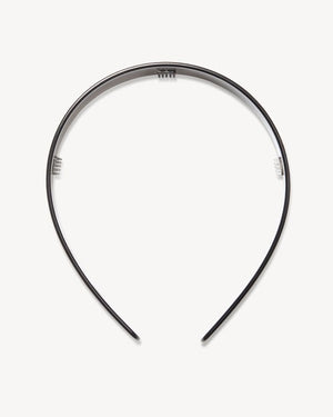 A woman in profile with a long braided ponytail wears a fuzzy beige sweater, gold hoop earring, and the MACHETE Wide Headband in Black by MACHETE. The background is plain off-white.